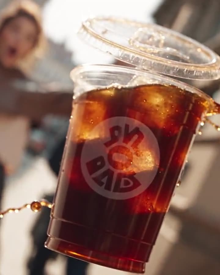 Ein Eiskaffeebecher fliegt in Zeitlupe durch die Luft
