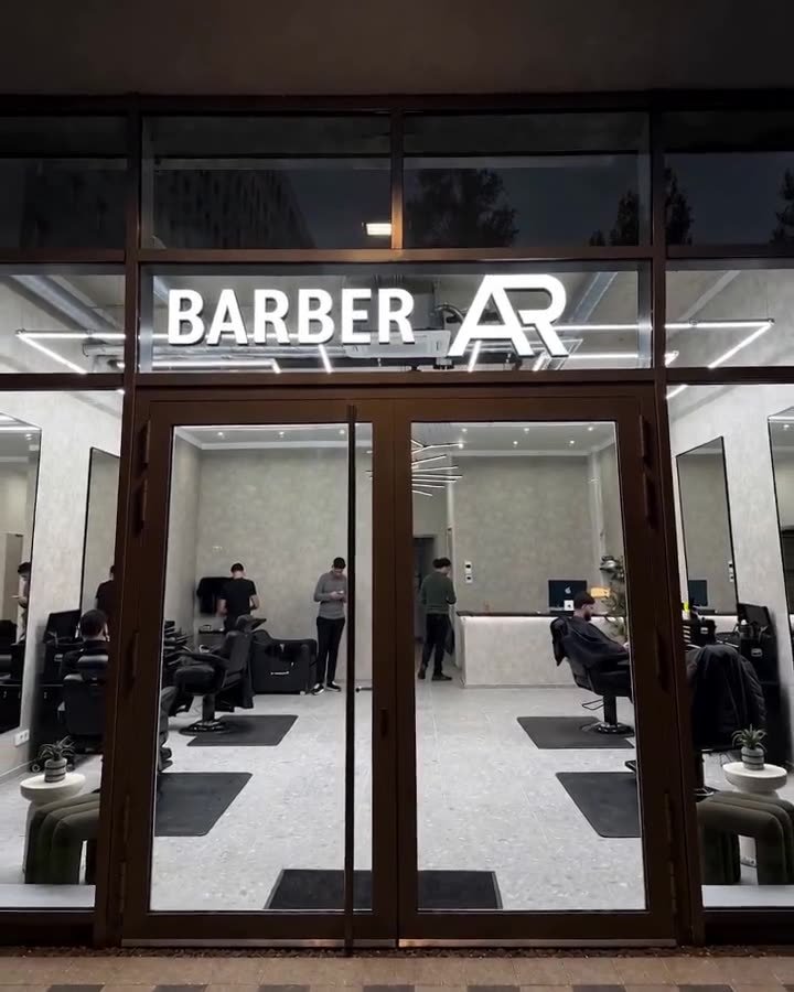 Beleuchtete Schaufensterfront eines Barbershops am Abend